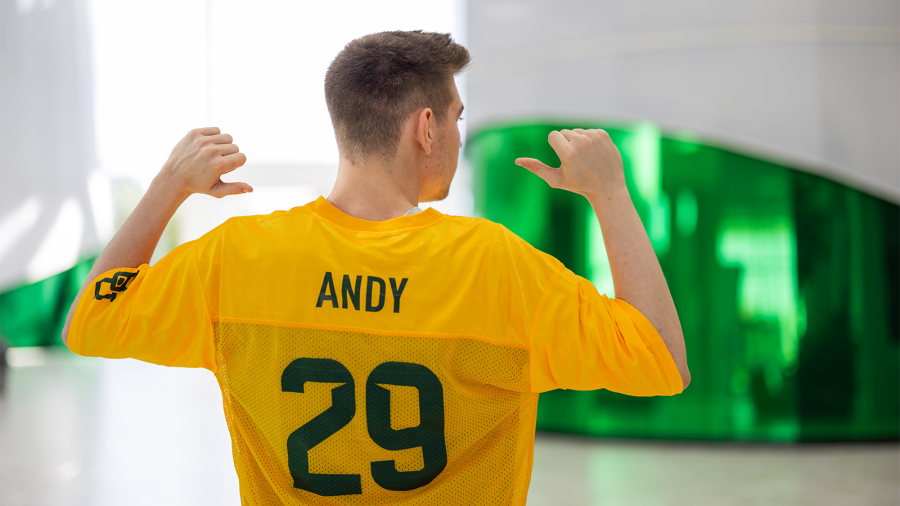 Baylor esports Andrew "Andy" Nolan points to the back of his gold Baylor Line jersey standing in the Hurd Welcome Center great hall